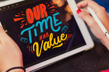 Tablet trzymany przez kobietę, na ekranie kolorowy napis Our Time Has Value