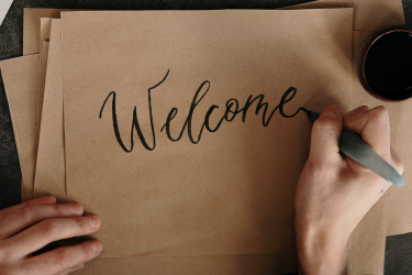 Napis Welcome w trakcie pisania na brązowym papierze
