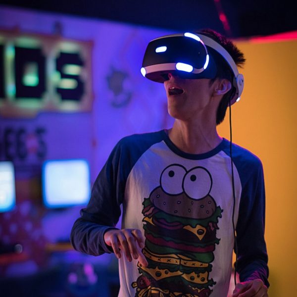 Młody chłopak w salonie gier zafascynowany googlami VR.