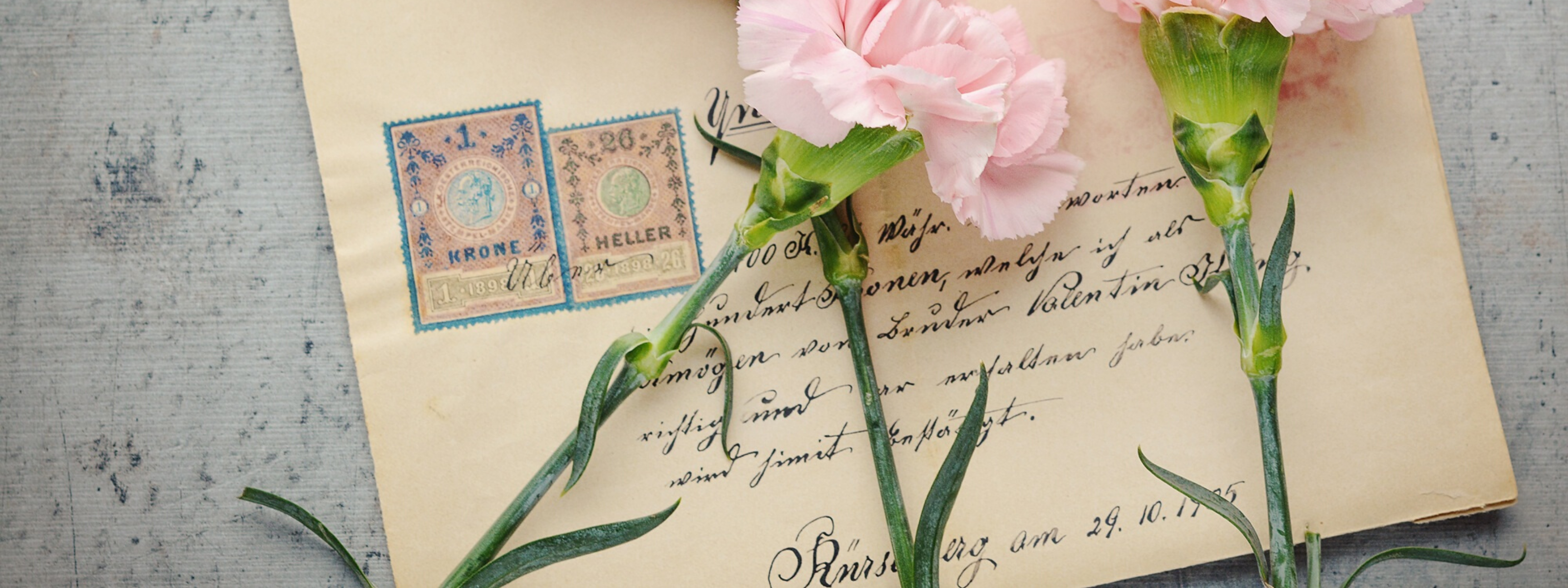 Różowe kwiaty z zielonymi liścmi na tle zaadresowanej koperty ze znaczkami.