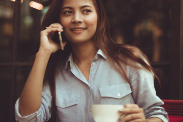 Rekruterka pracująca zdalnie w kawiarni - rozmawia przez telefon z kandydatem pijąc kawę