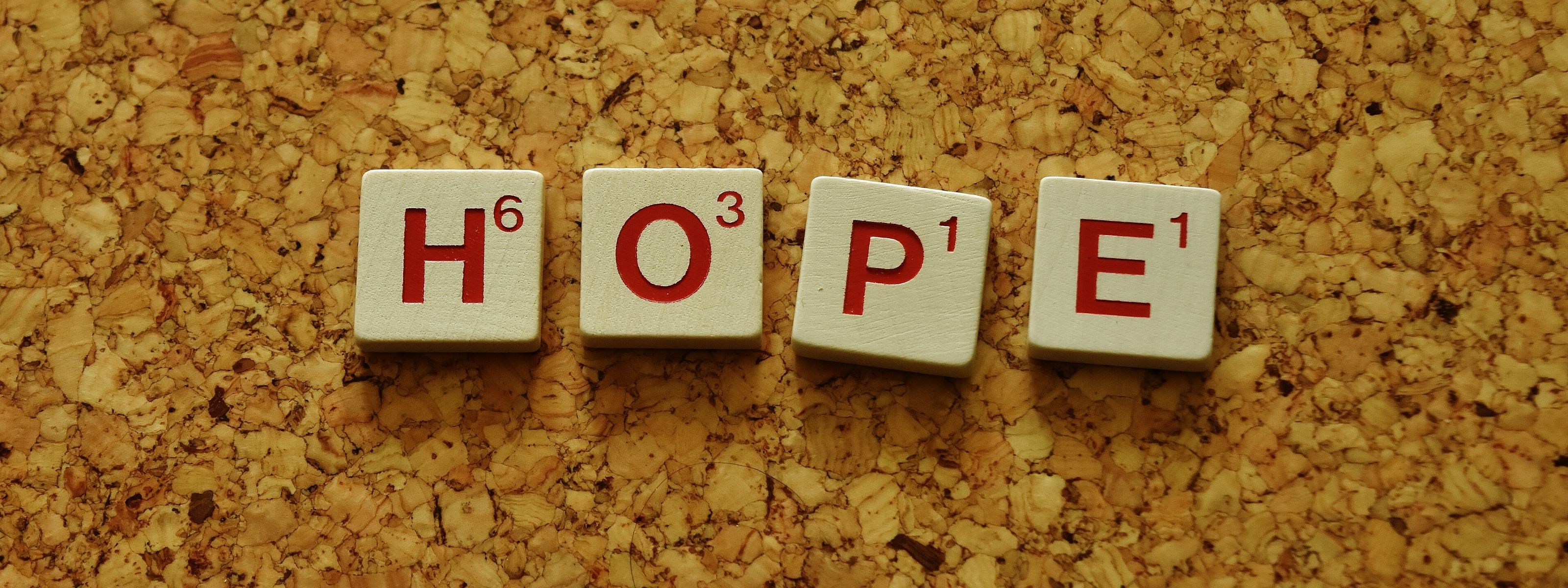 Napis hope ułożony z literek z gry Scrabble na korkowym tle.