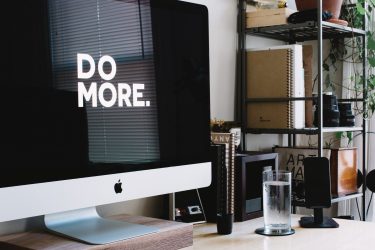 Komputer z wygaszaczem ekranu z napisem DO MORE w przestrzeni domowego biura.