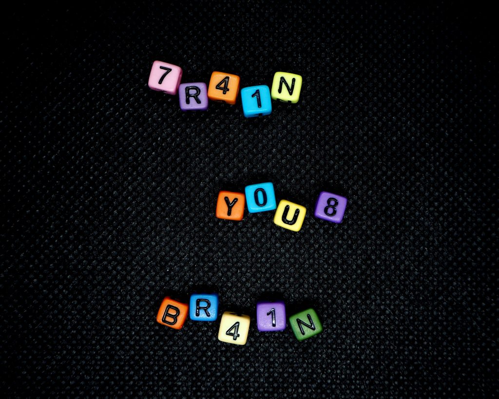 Grafika z napisami ułożonymi z oddzielnych, kolorowych kloców z literami: train your brain