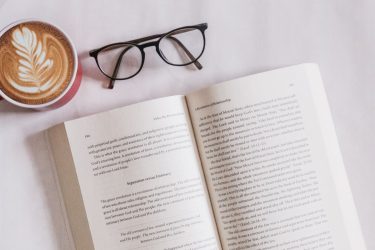 Storytelling - otwarta książka na białym obrusie, obok okulary do czytania i świeża kawa