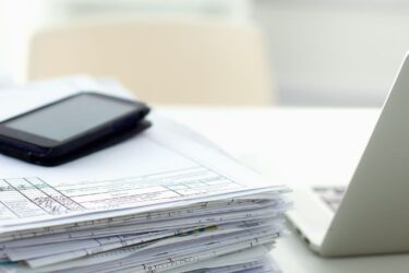 Dokumenty i telefon na biurku: Krajowa Infolinia Podatkowa – zobacz spis numerów i zakres informacji