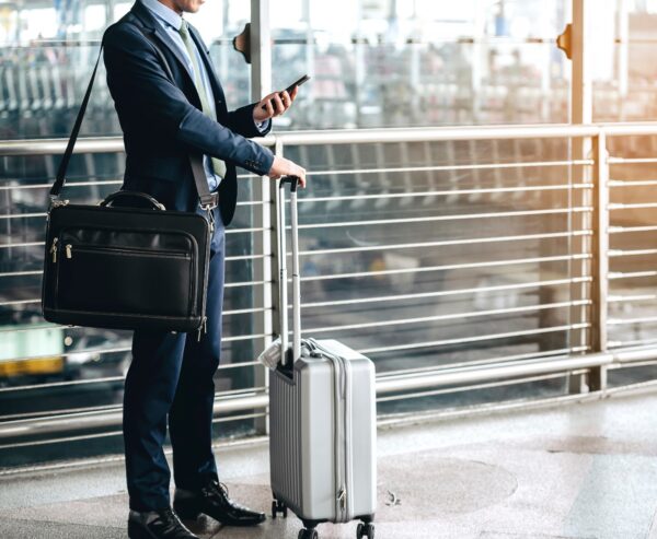 Mężczyzna z walizką i laptopem czeka na dworcu na dalszą podróż