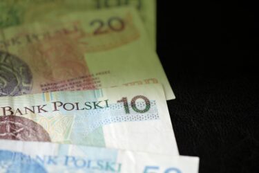 Banknot 20 złotych, 10 złotych i 50 złotych leża na sobie na ciemnym tle