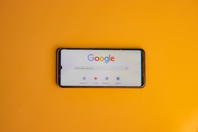 Telefon z wyświetloną przeglądarką Google leży na pomarańczowym tle