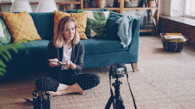 Influencerka siedząca przed aparatem reklamuje produkt w ramach umowy barterowej