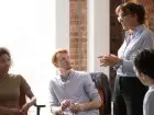 Facylitator - kobieta-liderka-trenerka w średnim wieku przemawia przed zespołem w biurze