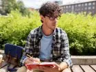 Iberysta - mężczyzna w okularach siedzący na ławce z książką