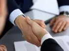 Umowa o pracę - dwie osoby podające sobie dłonie nad umową