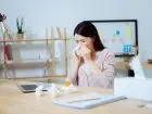 Kobieta chora, czyszcząca nos przy biurku