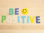 Ułozony na blacie napis z filcu "be positive" i uśmiechnięta buzia
