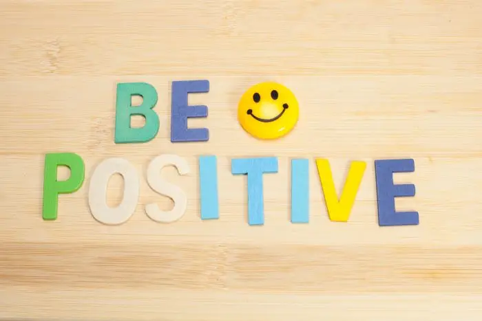 Ułozony na blacie napis z filcu "be positive" i uśmiechnięta buzia