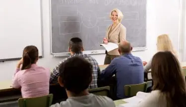 Nauczycielka przed słuchaczami w sali, przy tablicy
