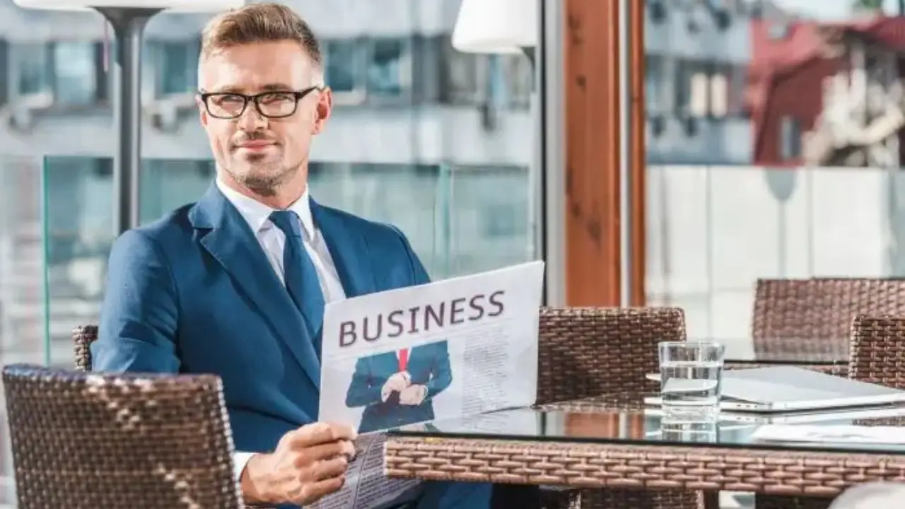 Elegancko ubrany mężczyzna trzymający gazetę z napisem biznes