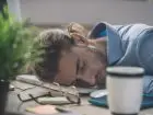Rozbudzenie na home office - mężczyzna śpiący na biurku, na klawiaturze