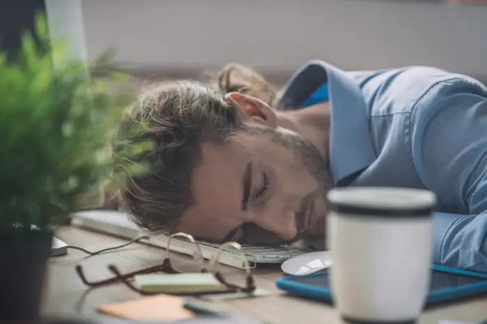 Rozbudzenie na home office - mężczyzna śpiący na biurku, na klawiaturze