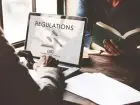 KRS - mężczyzna piszący na laptopie - na ekranie napis "regulations"