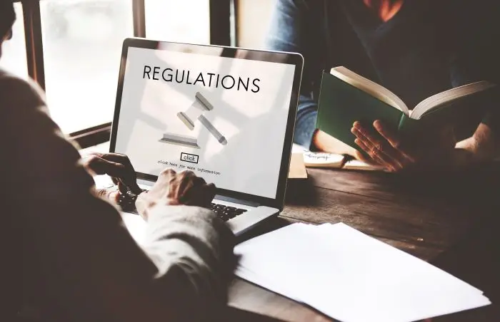 KRS - mężczyzna piszący na laptopie - na ekranie napis "regulations"