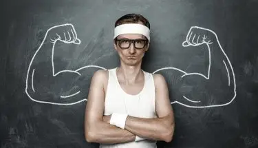 MultiSport - pracownik w okularach i sportowym ubraniu stoi przy tablicy na której narysowane są umięśnione ramionaórej narysowane są