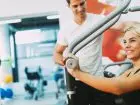 Multisport - kobieta ćwicząca na siłowni z trenerem personalnym