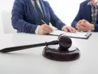 PIP - symboliczne zdjecie przedstawiające młotek sędziowski na stole, w tle dwóch mężczyzn elegancko ubranych