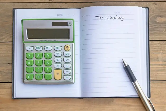 Zeszyt z napisem "tax planing" i położony na nim kalkulator