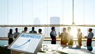 Przedsiębiorstwo - spotkanie wielu ludzi w wysokim budynku i tablet z napisem “business”