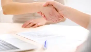 Umowa przedwstępna - uścisk dłoni dwóch osób nad dokumentem