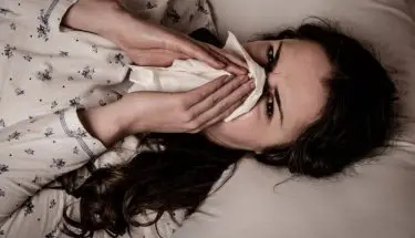 Kobieta czyszcząca nos chusteczką