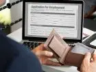 Podanie o pracę - mężczyzna przed laptopem z portfelem w dłoniach