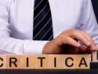 Krytyka w pracy - napis critical układany z locków przez mężczyznę w koszuli