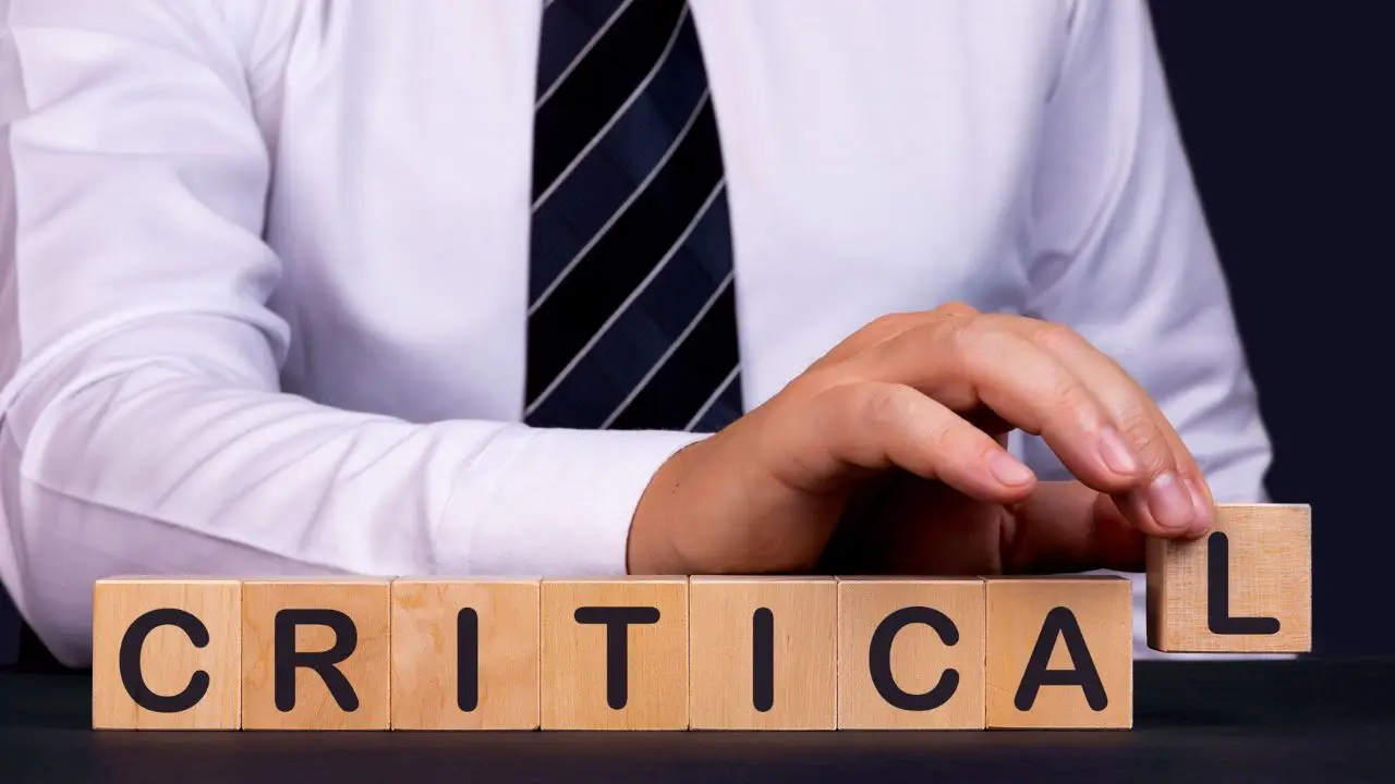 Krytyka w pracy - napis critical układany z locków przez mężczyznę w koszuli