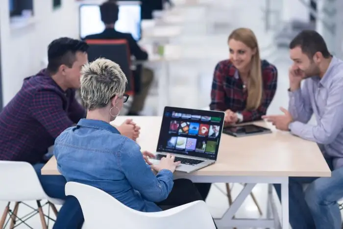 Microsoft teams - ludzie siedzący przy biurku w pracy, kobieta trzyma laptopa