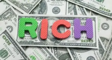 Banknoty dolary a na nich napis "rich" z klocków