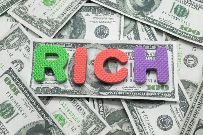 Banknoty dolary a na nich napis "rich" z klocków