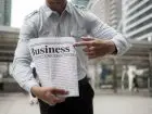 Mężczyzna trzymający gazetę z napisem business