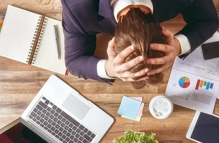 Stres w pracy - zestresowany pracownik załamuje ręce nad biurkiem