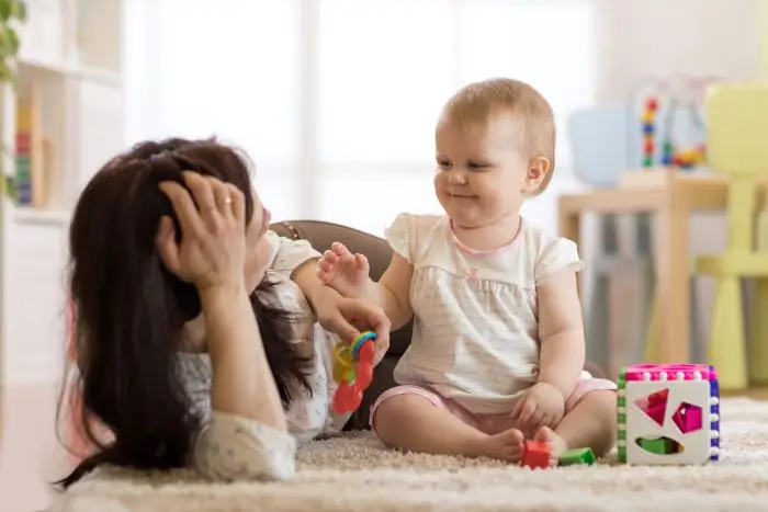 Mama bawiąca się z dzieckiem na dywanie