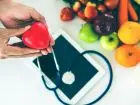 Jak sprawdzić czy jest się ubezpieczonym - figurka serca trzymana w dłoni, nad sprzętem medycznym, tabletem i owocami