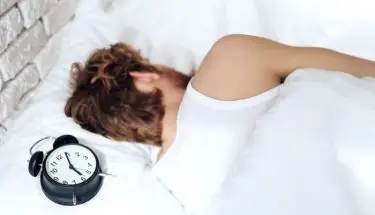 Kalkulator snu - osoba śpiąca z zegarkiem przy głowie