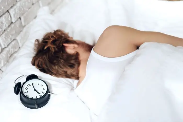 Kalkulator snu - osoba śpiąca z zegarkiem przy głowie