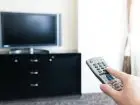 Pilot w dłoni, skierowany w stronę telewizora