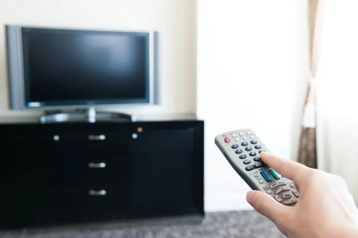 Pilot w dłoni, skierowany w stronę telewizora