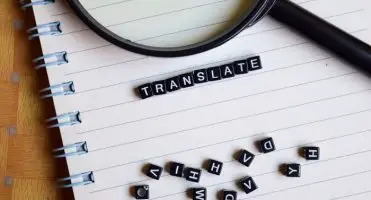 Tłumacz tekstów - notatnik, a na nim lupa i napis "translate" ułożony z klocków