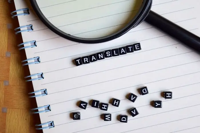 Tłumacz tekstów - notatnik, a na nim lupa i napis "translate" ułożony z klocków