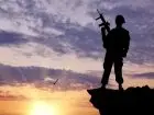 Żołnierz stojący na skarpie z bronią